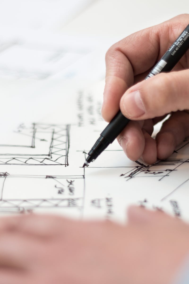 Close-up of hand drawing intricate technical designs on blueprint with pen, ideal for engineering or architecture themes.