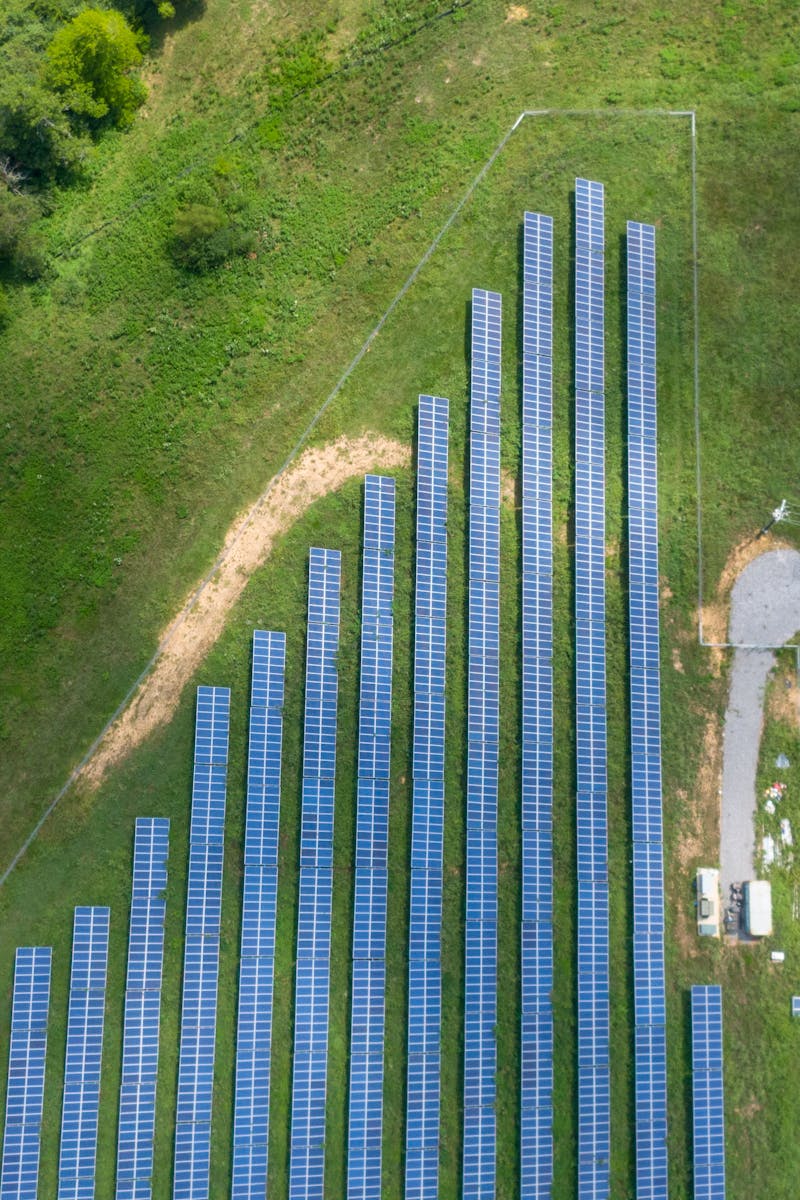 Aerial view showing a solar panel array in a lush rural landscape with a road.